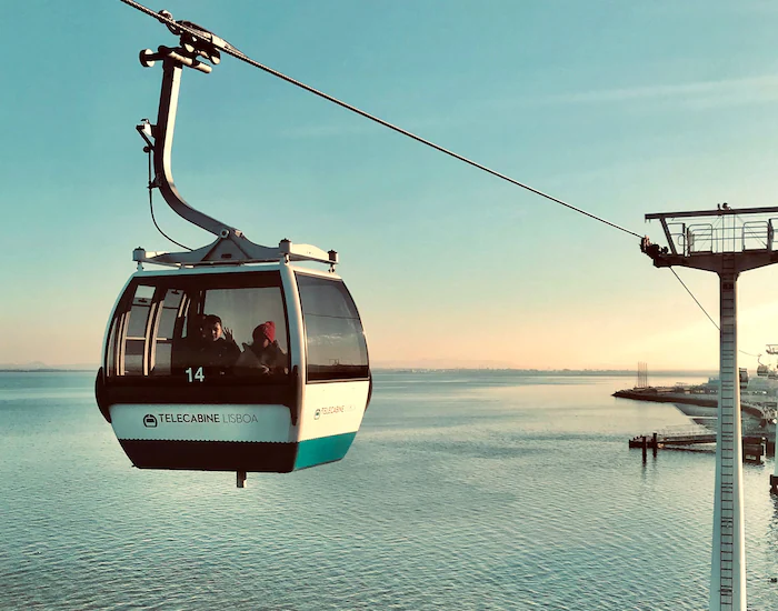 Cable car cabin crossing over the water near Lisbon’s Oceanarium with sunset colors on the horizon