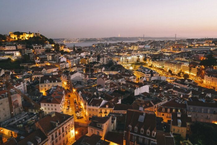 Scenic view of Lisbon rooftops with the Tagus River and bridge in the background during golden hour