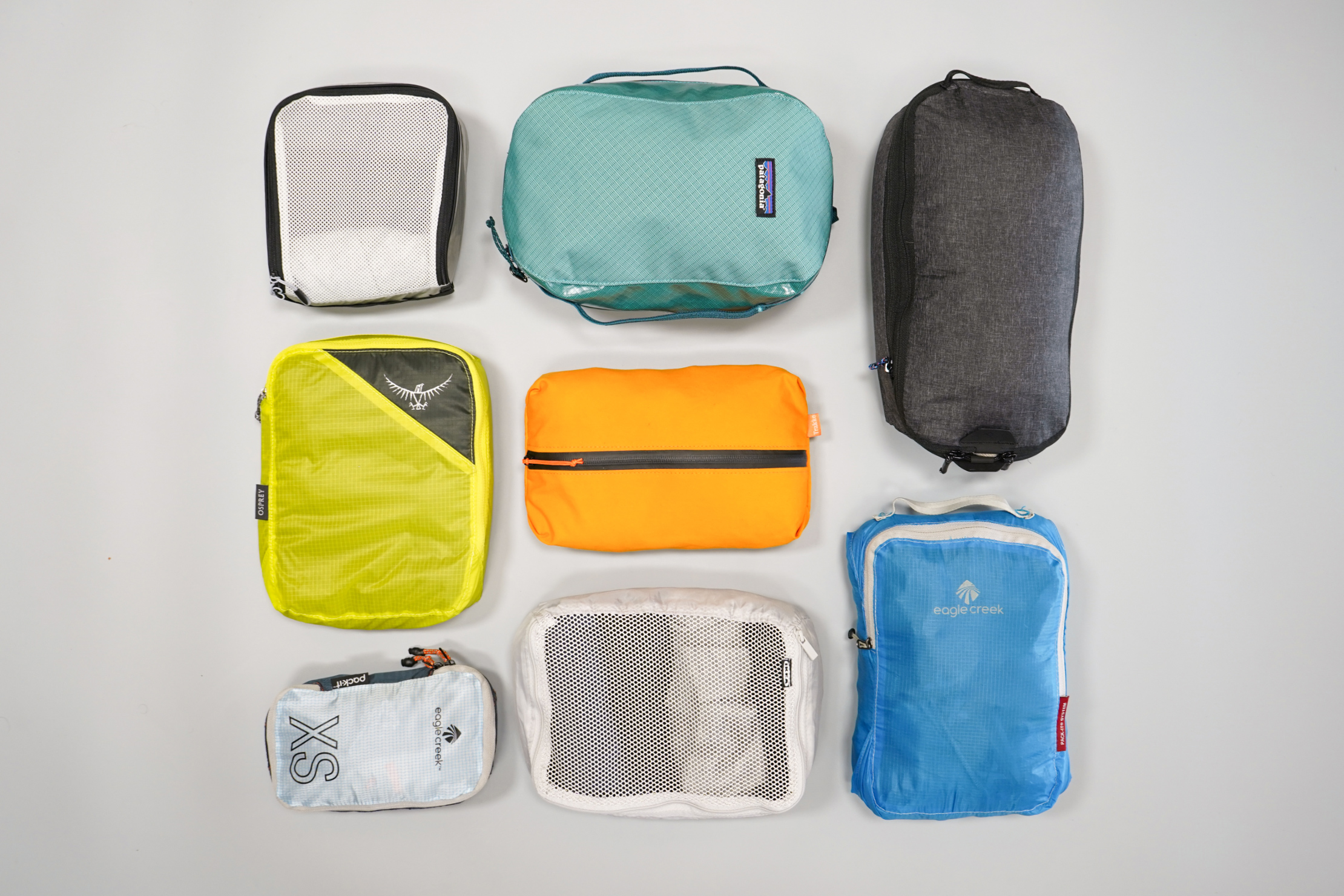 Flat-lay of various travel packing cubes arranged neatly on a pale background
